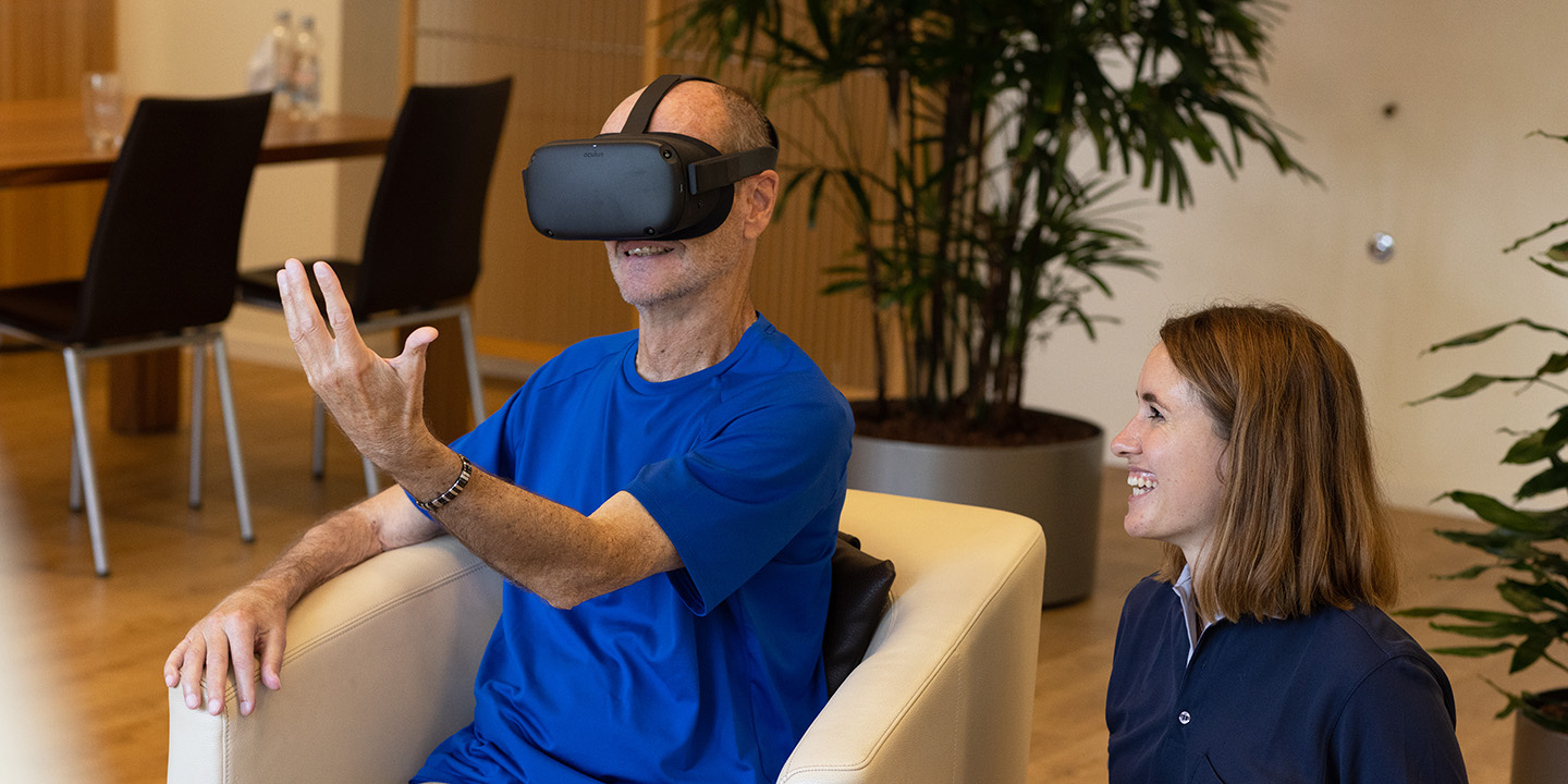 Patient mit einer VR-Brille neben einer Pflegerin.