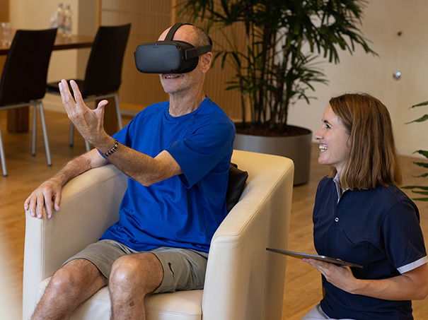 Patient mit einer VR-Brille neben einer Pflegerin.