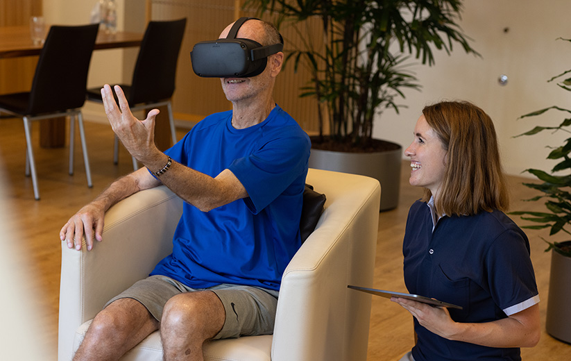 Patient mit einer VR-Brille neben einer Pflegerin.