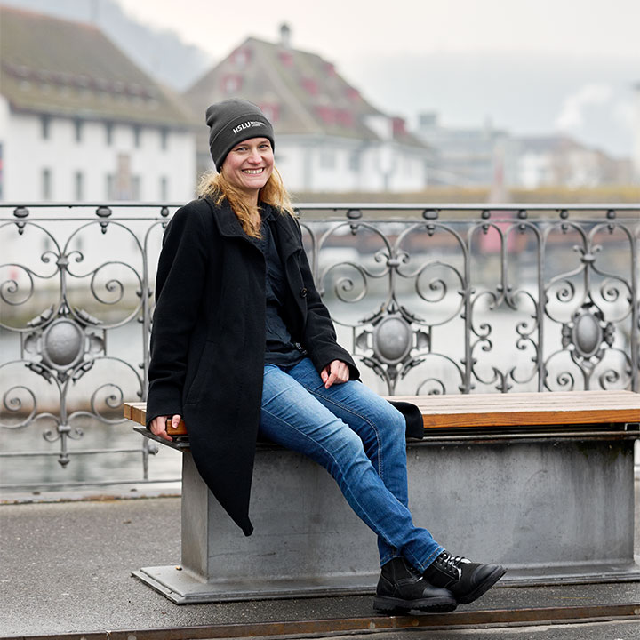 Die Quantenkryptografie-Forscherin Esther Hänggi sitzt auf einer Bank an der Reuss in der Stadt Luzern. Sie trägt blaue Jeans, eine schwarze Jacke und eine schwarze Mütze.