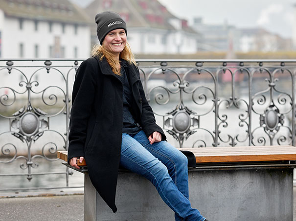 Die Quantenkryptografie-Forscherin Esther Hänggi sitzt auf einer Bank an der Reuss in der Stadt Luzern. Sie trägt blaue Jeans, eine schwarze Jacke und eine schwarze Mütze.