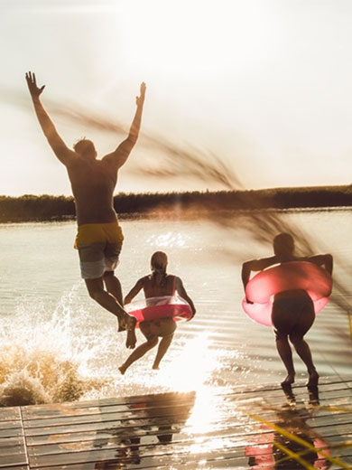 Ein Erwachsener und zwei Kinder hüpfen in den See. Ein Erwachsener und zwei Kinder hüpfen in den See.