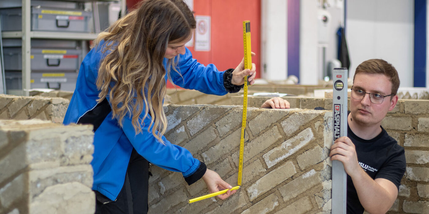 Zwei Personen bauen eine Lehmbauwand Zwei Personen bauen eine Lehmbauwand