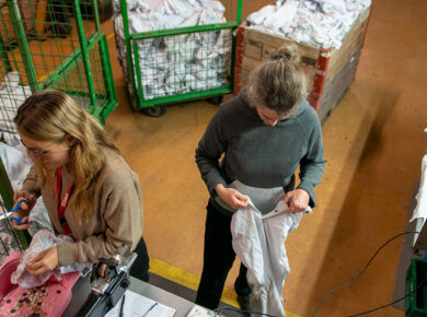 Zwei Frauen arbeiten mit Altkleidern um Textilrecycling zu fördern