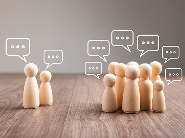 Mehrere Holzfiguren mit Sprechblasen in einer Diskussion